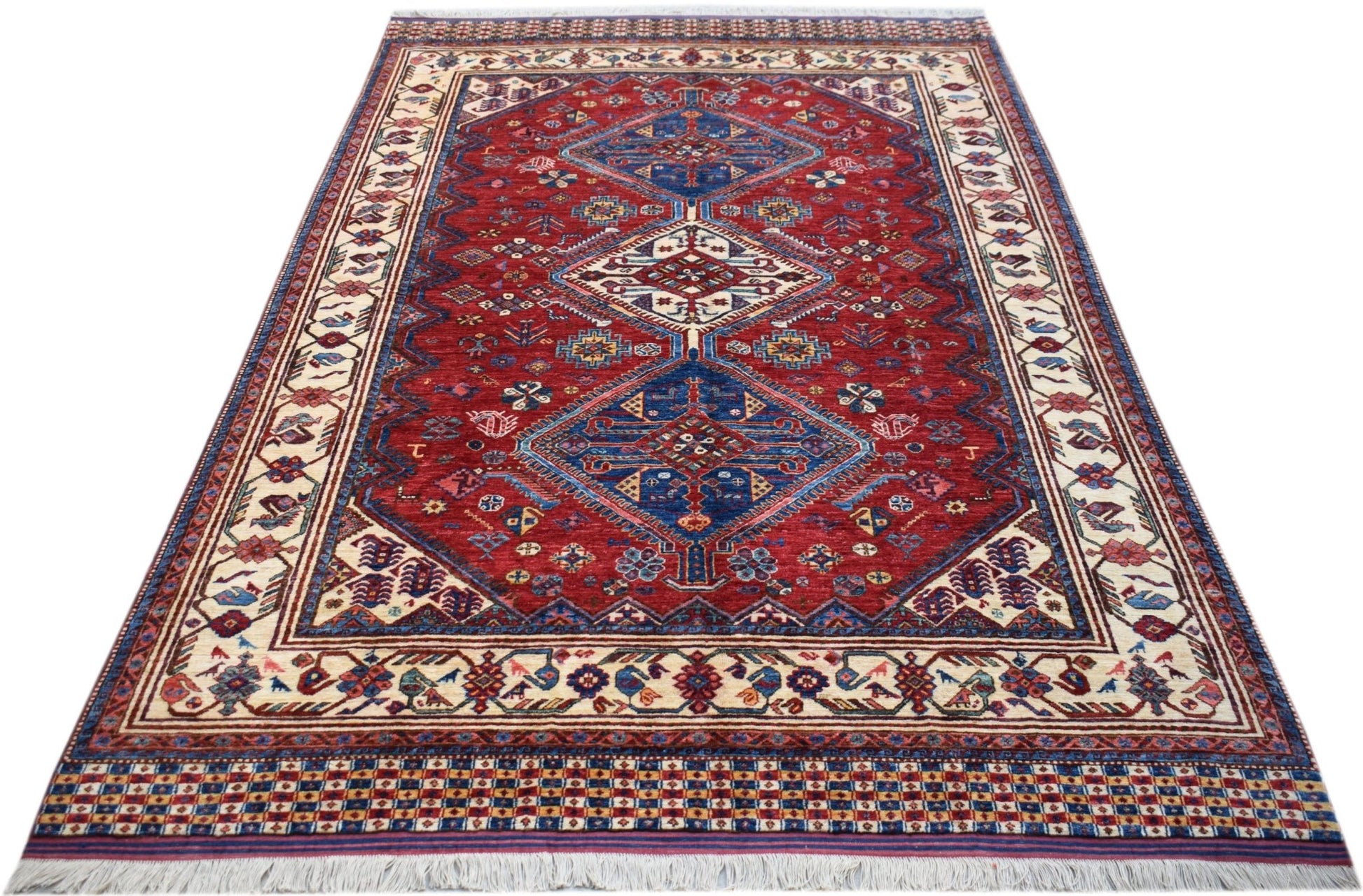 Handwoven Afghan Herati rug featuring a red field with blue diamond medallions and cream borders.