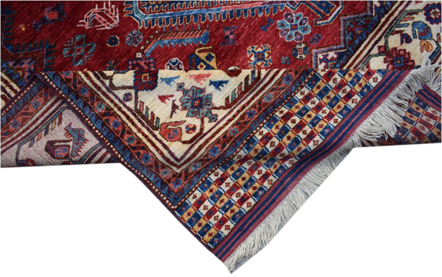 A handwoven Afghan Herati rug featuring a red field with intricate blue and cream geometric motifs.