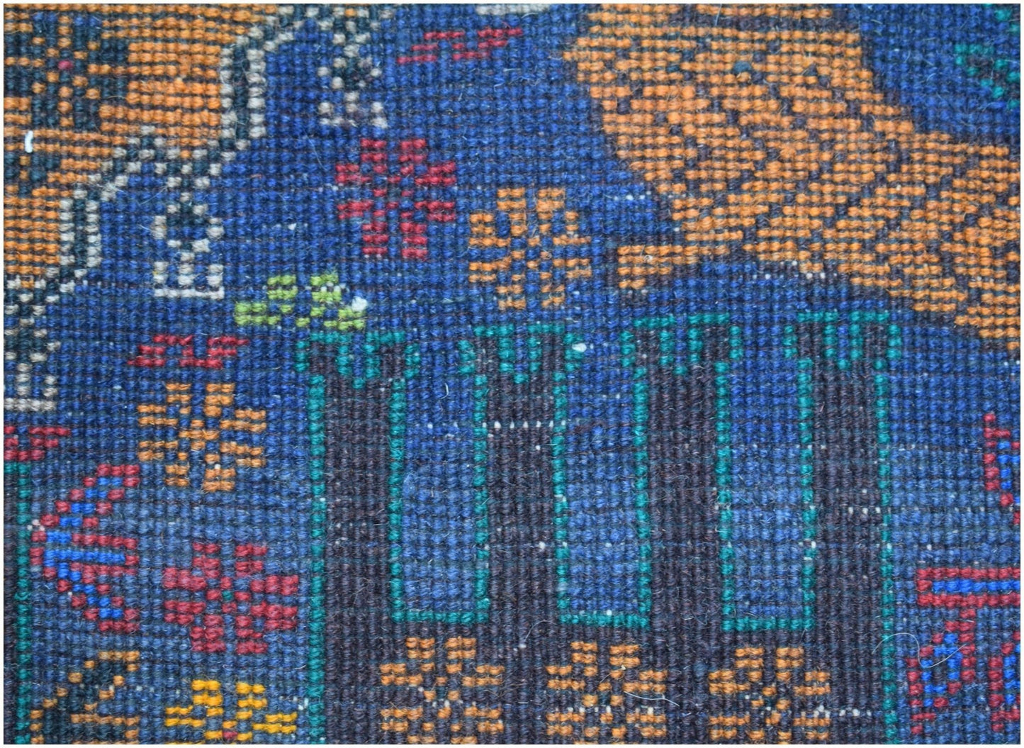 A close-up of a handmade Afghan wool runner featuring intricate floral and geometric patterns.