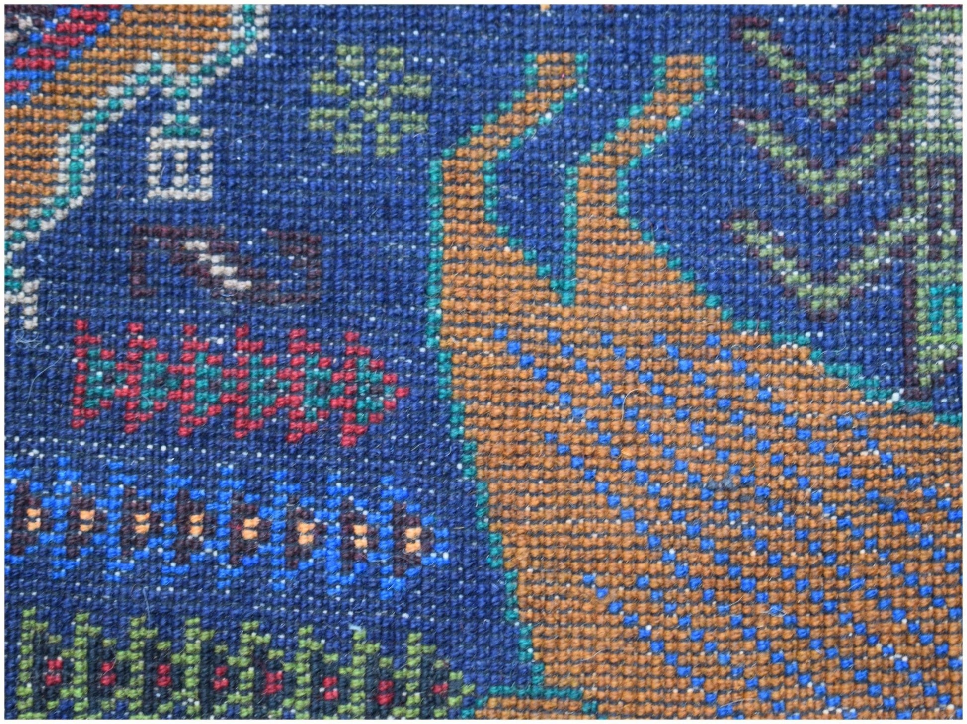 A close-up of a handmade Afghan wool runner featuring a detailed hunting scene on a blue background.
