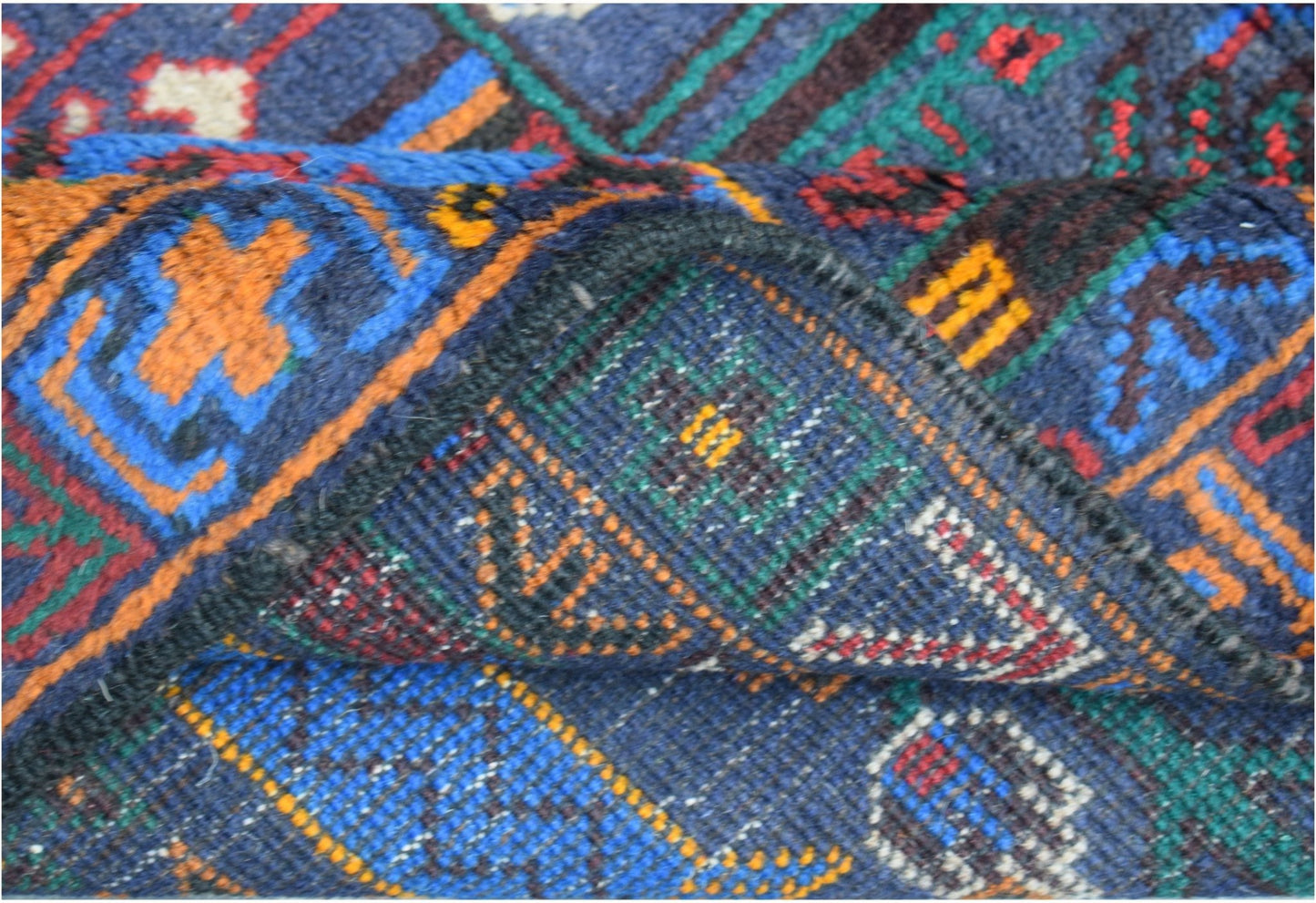 A close-up view of a handmade Afghan wool runner featuring a blue background and geometric patterns.