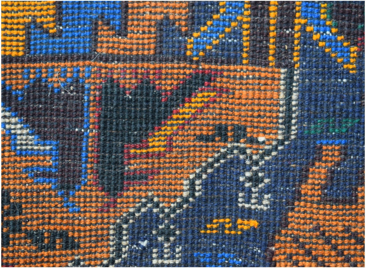 A close-up of a handmade Afghan wool runner featuring a geometric hunting scene in blue and orange.
