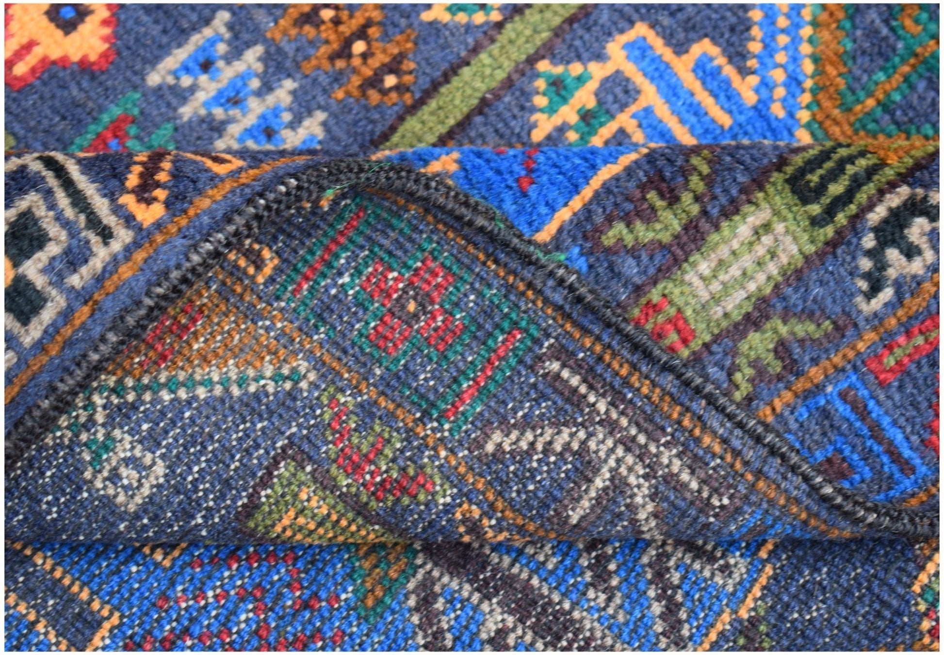 A handmade Afghan wool runner featuring a blue background with intricate geometric hunting motifs.