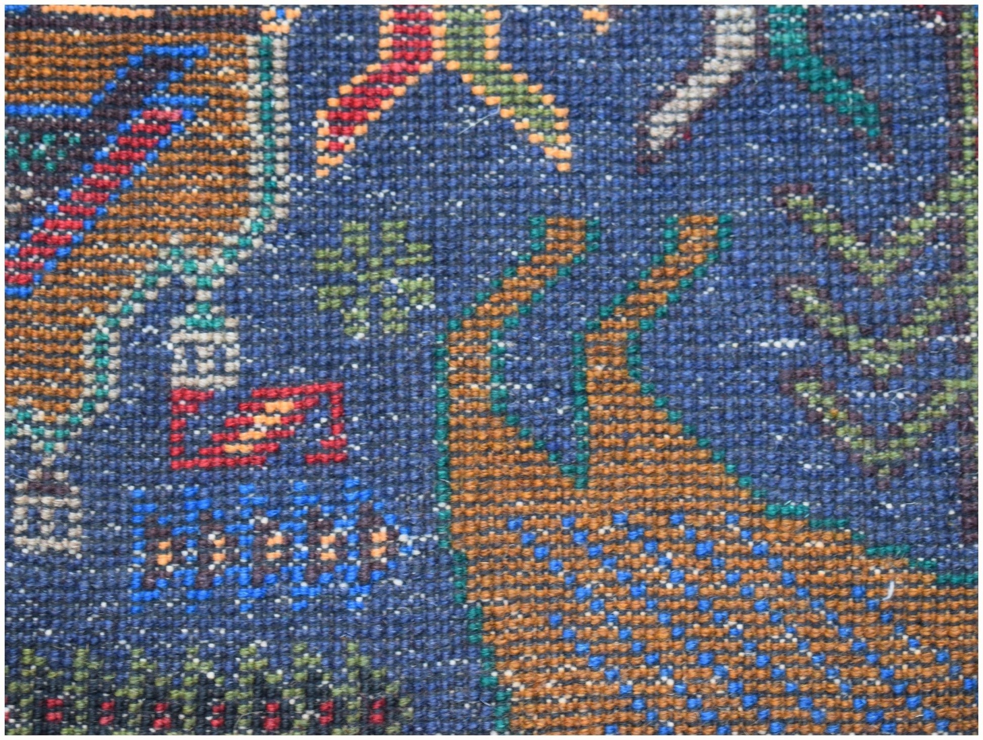 A close-up of a handmade Afghan wool runner featuring a detailed hunting scene on a blue background.