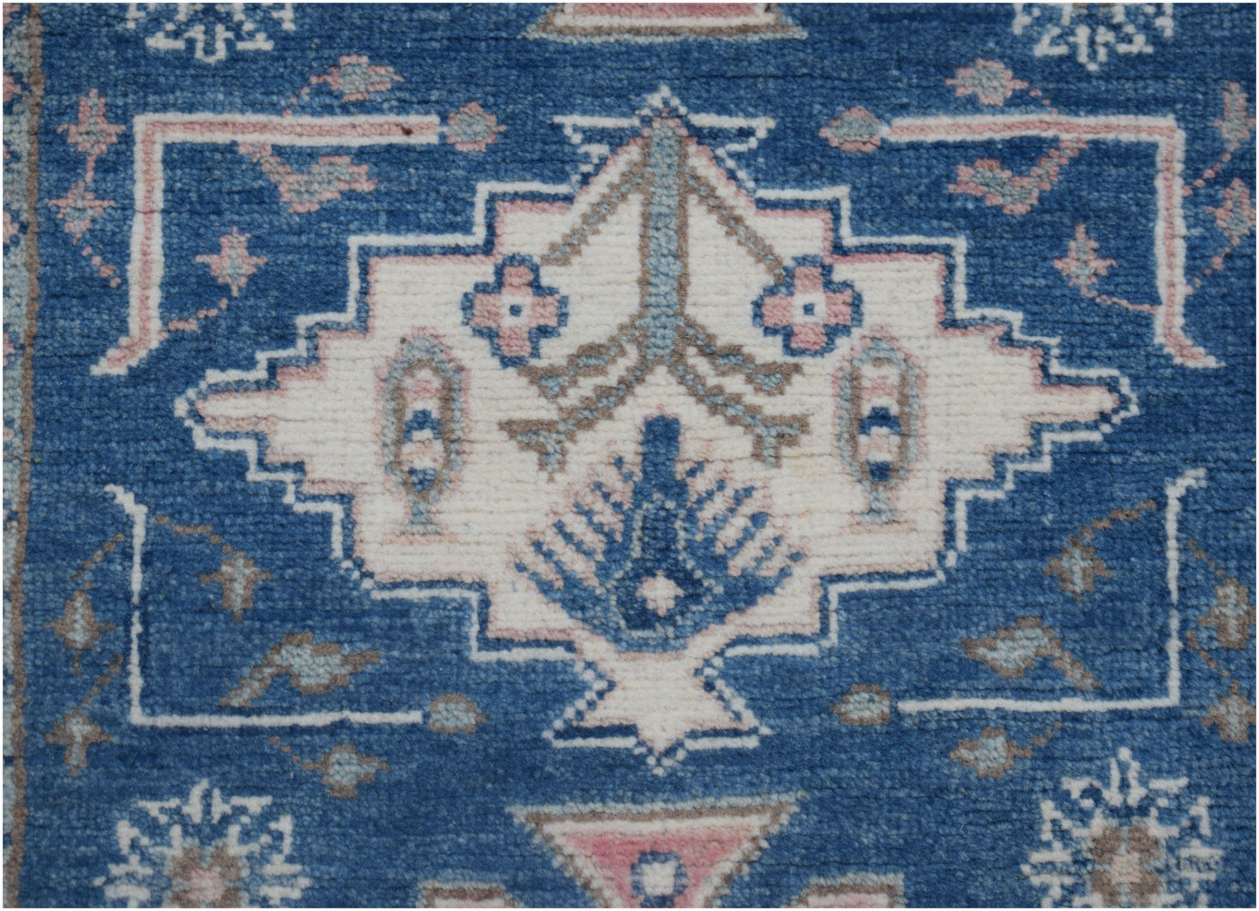 Handmade Afghan Kazakh runner featuring a central geometric floral motif on a blue wool background.