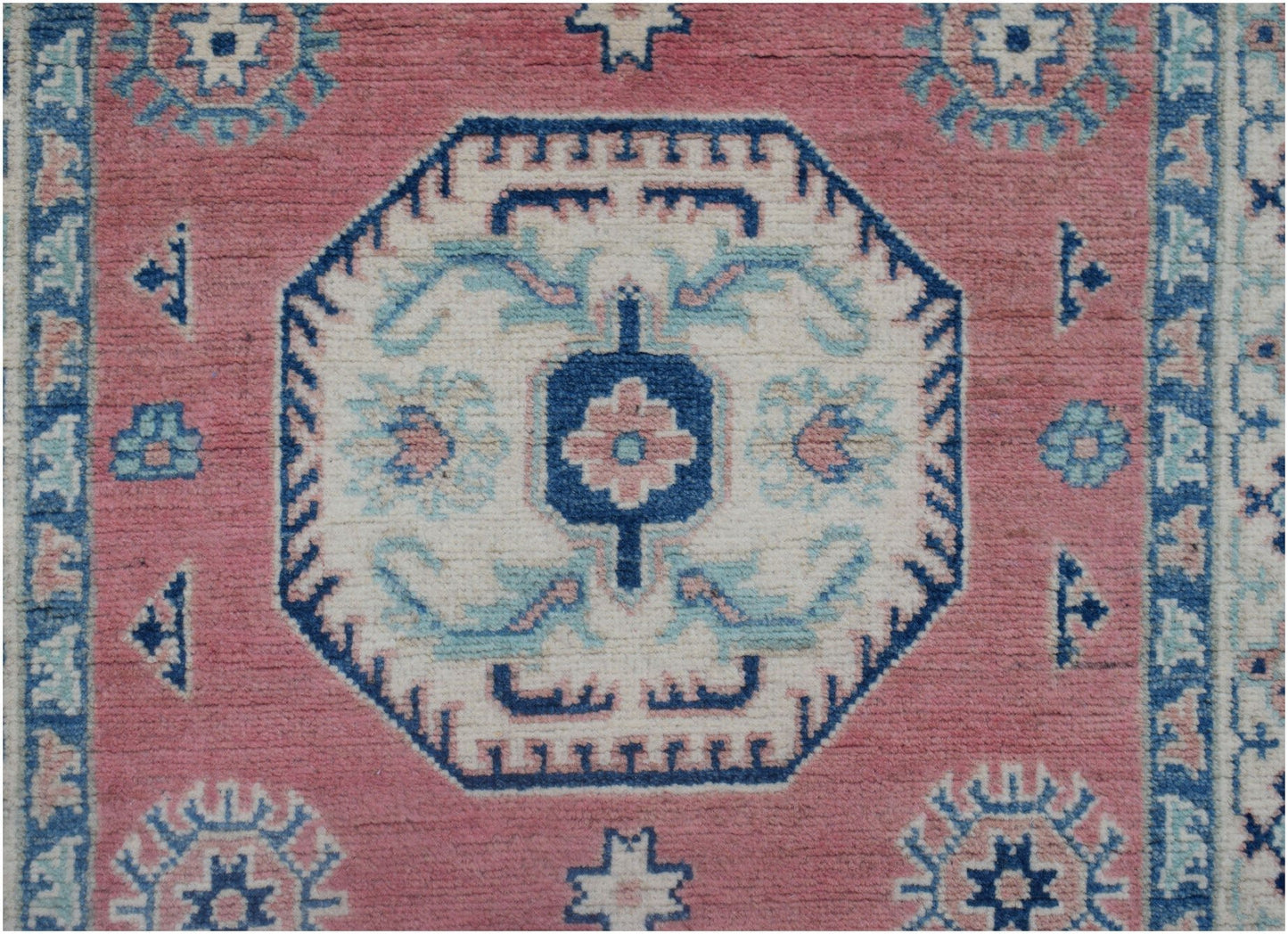 Handmade Afghan Kazakh runner rug featuring a central geometric medallion on a pink wool field.