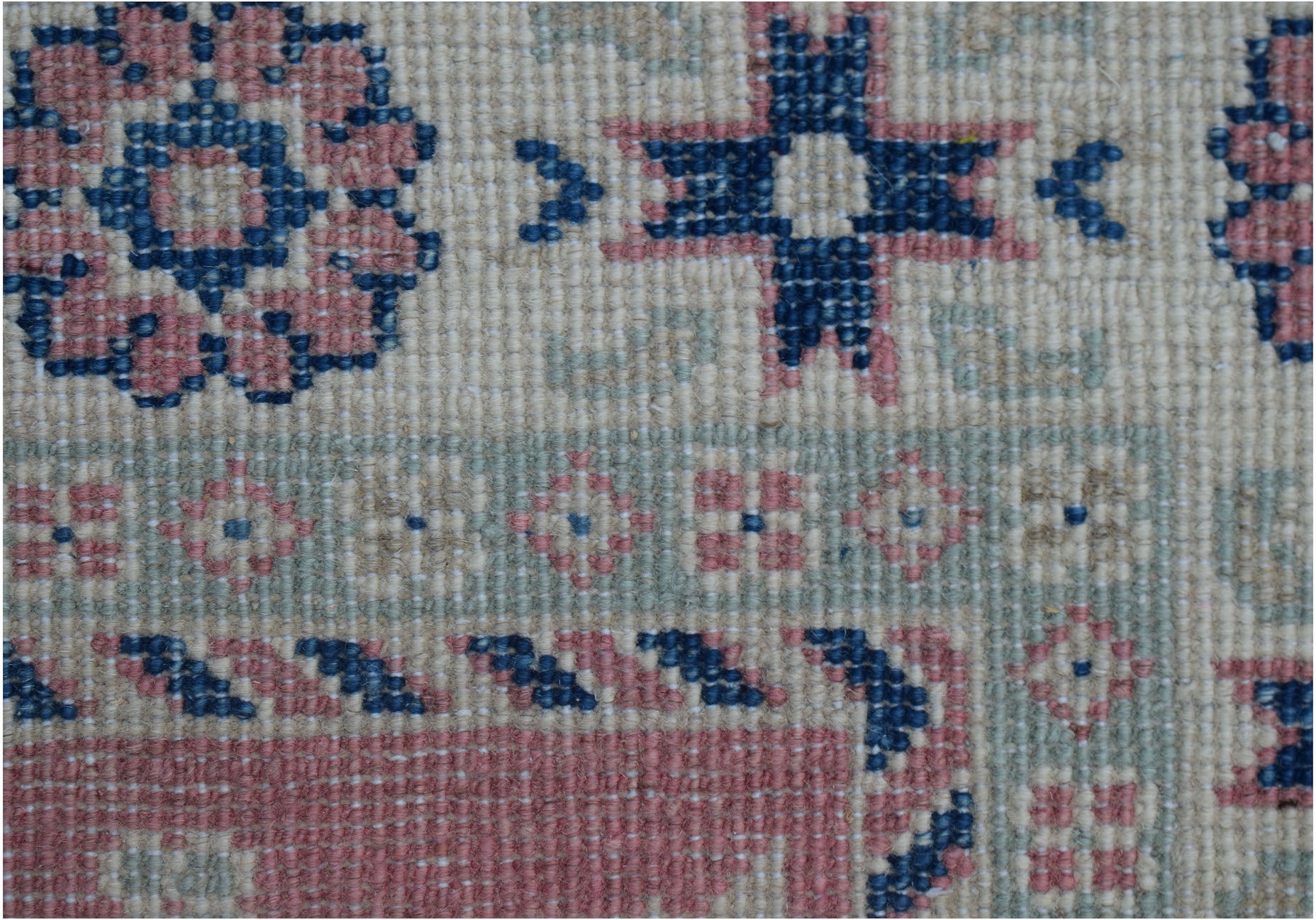 A close-up of an Afghan Kazakh runner featuring traditional geometric motifs in blue and pink wool.