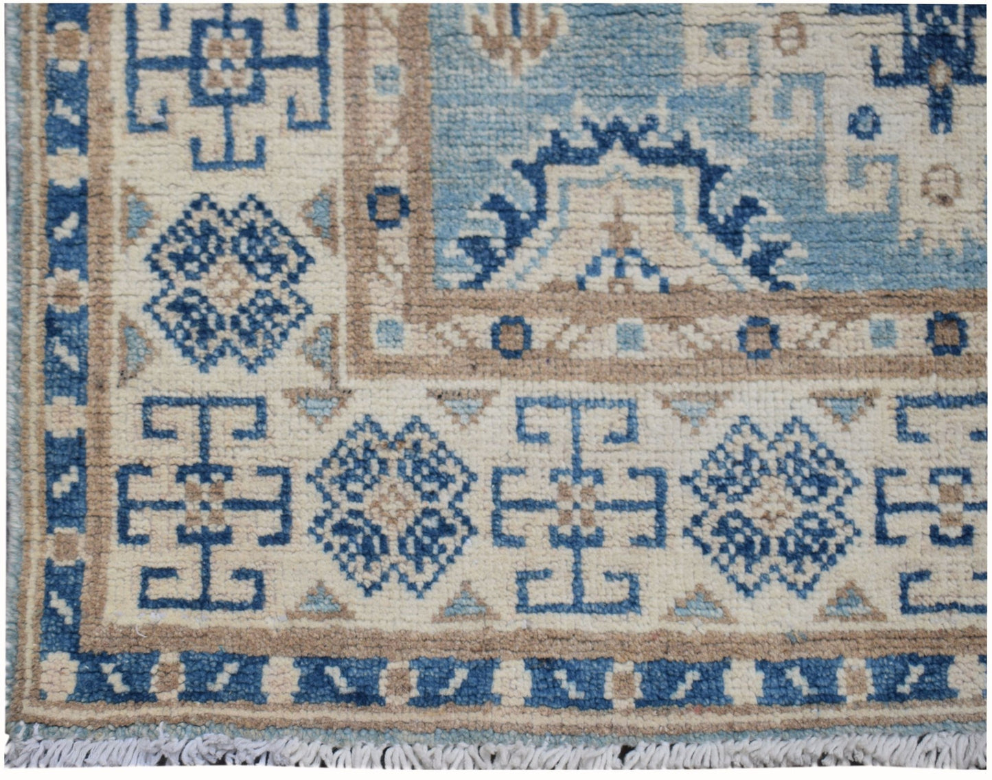 Handmade Afghan Kazakh runner rug featuring geometric blue and beige patterns on a cream field.