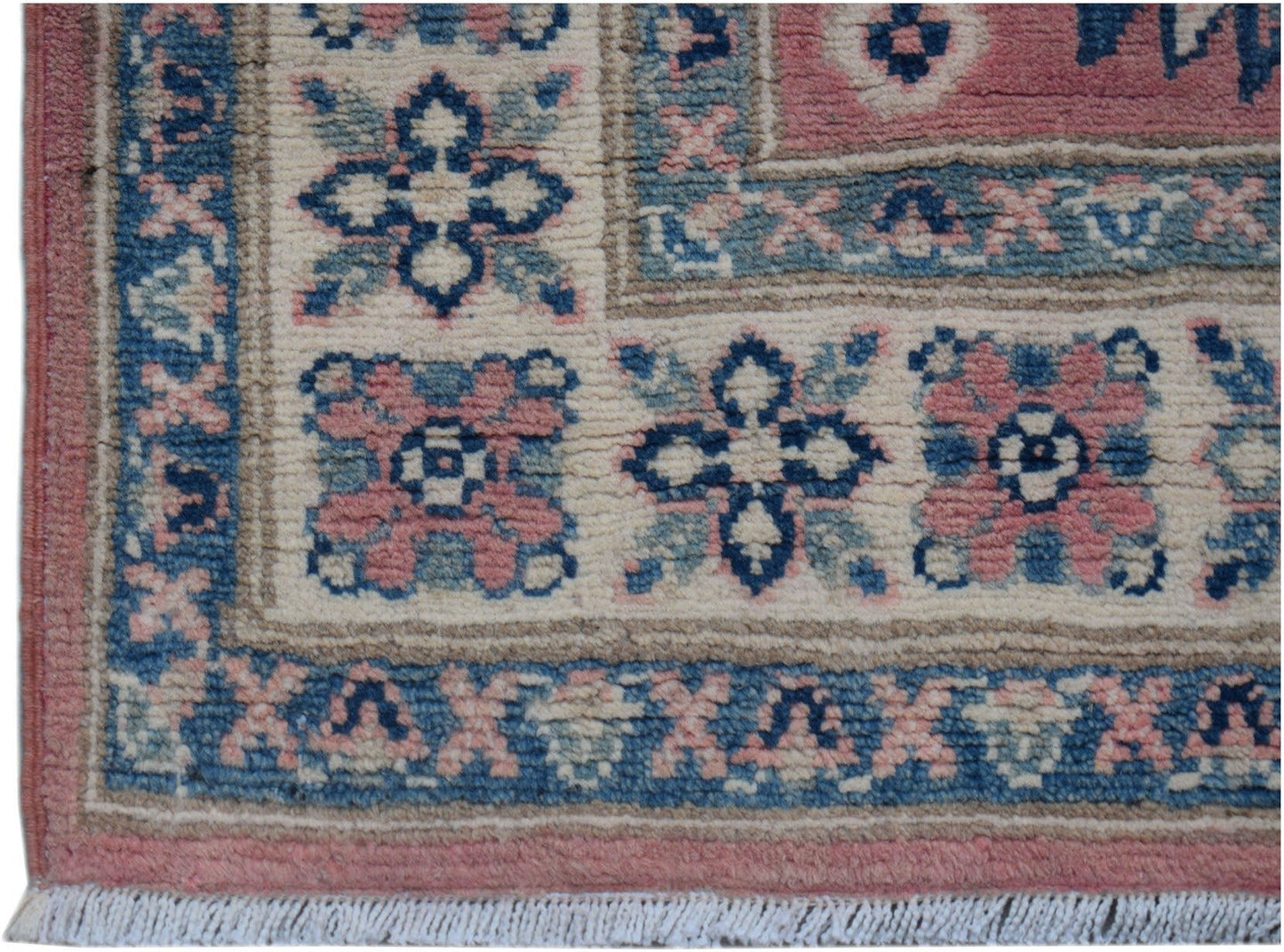 A handmade Afghan Kazakh runner featuring traditional floral motifs in pink, blue, and cream wool.