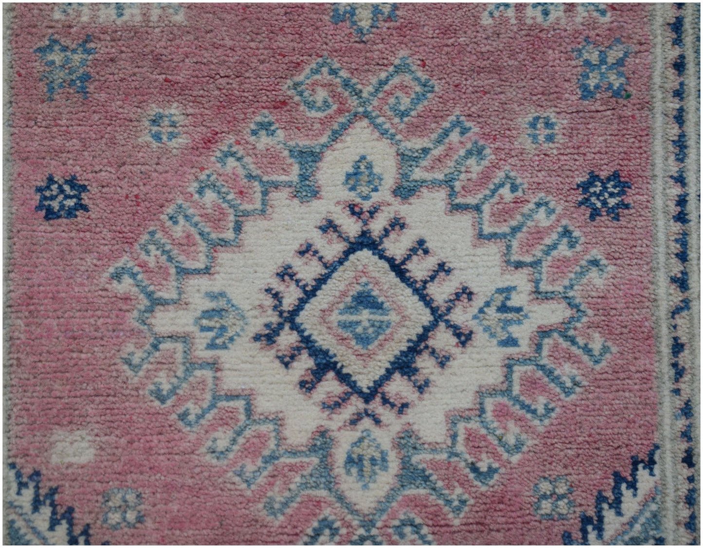 An Afghan Kazakh runner featuring a central geometric diamond motif in blue, white, and pink.