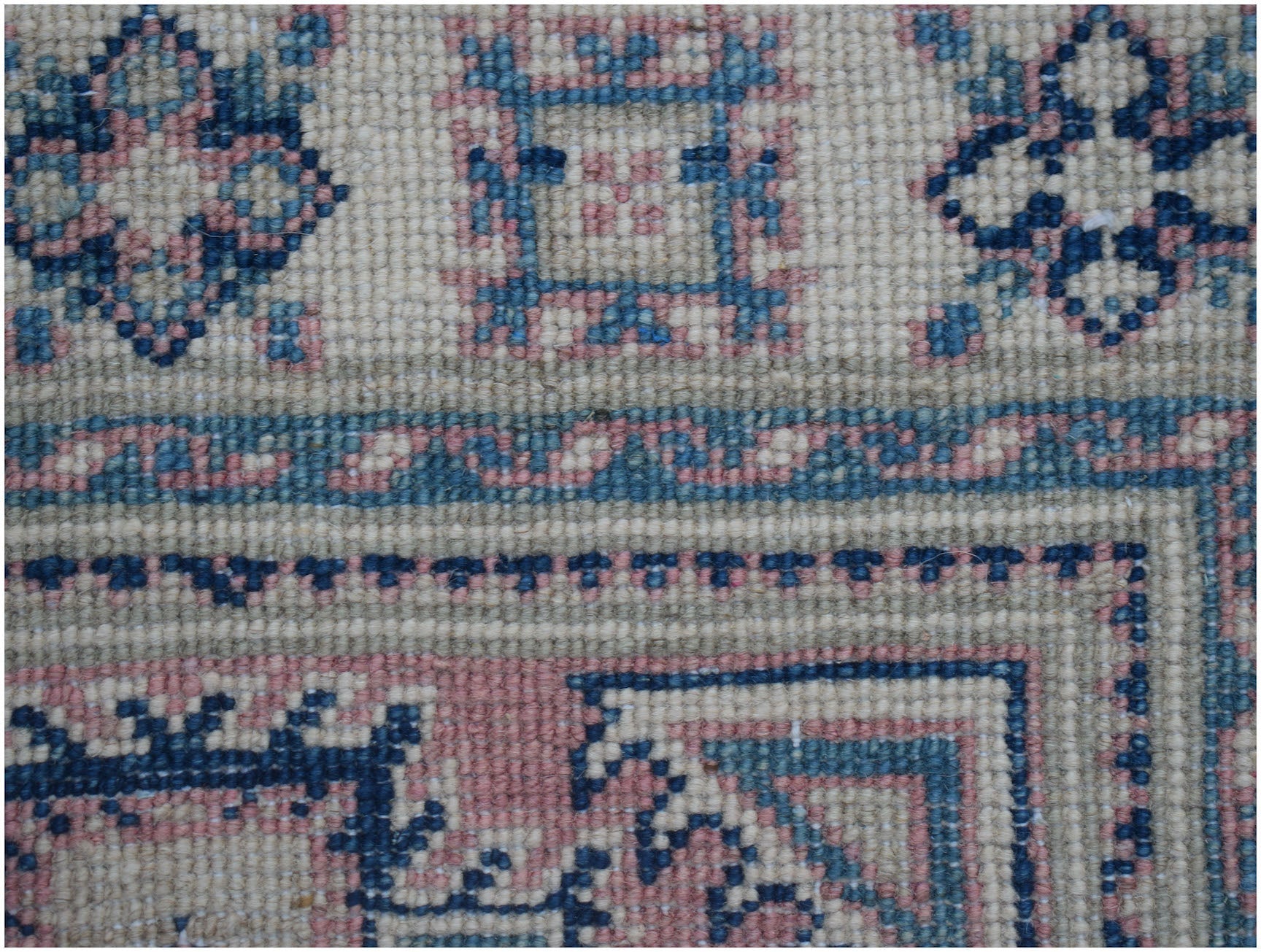 A handmade Afghan Kazakh runner featuring traditional geometric motifs in blue, pink, and cream.