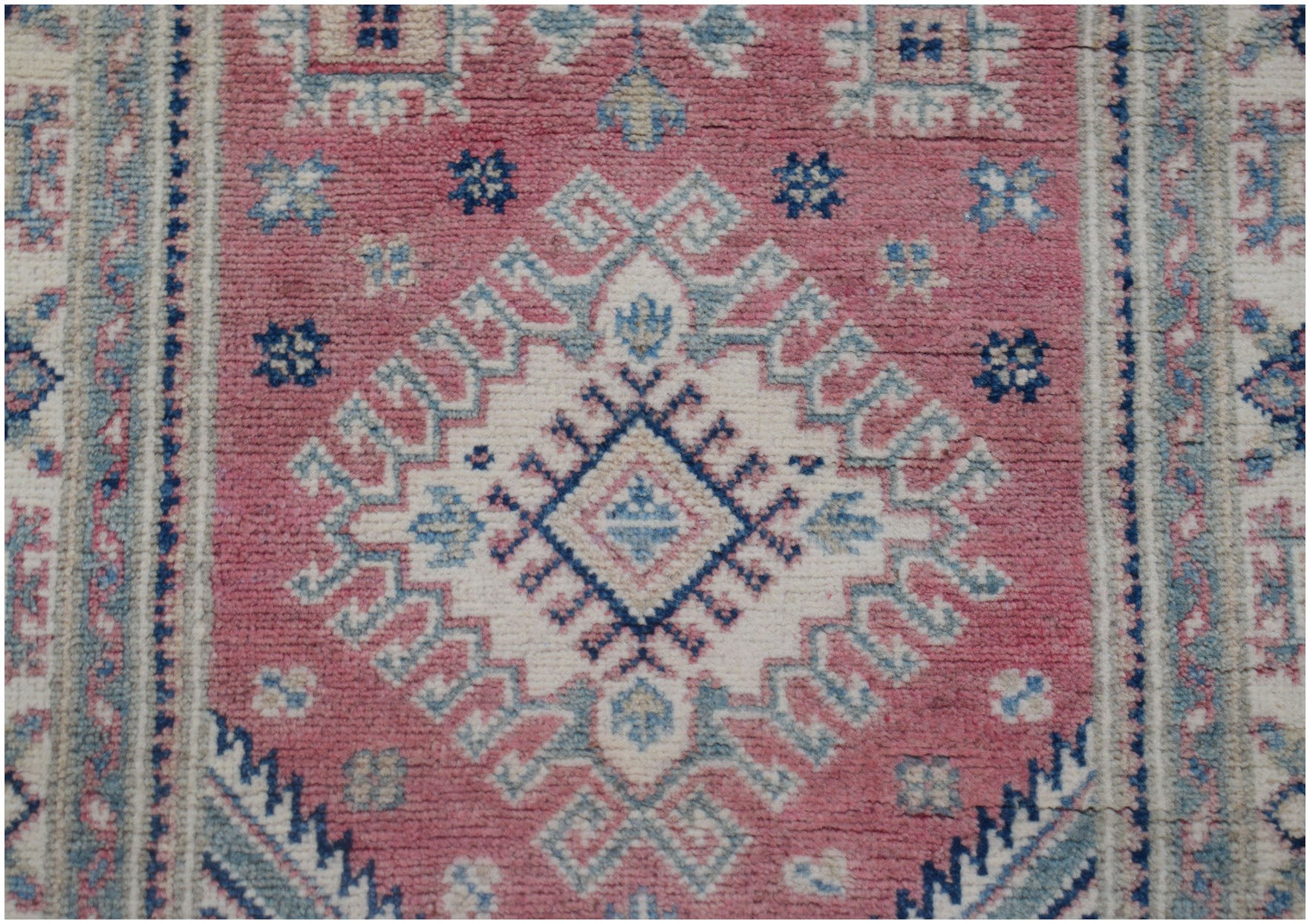 Handmade Afghan Kazakh runner rug featuring a geometric diamond pattern in pink, blue, and cream.
