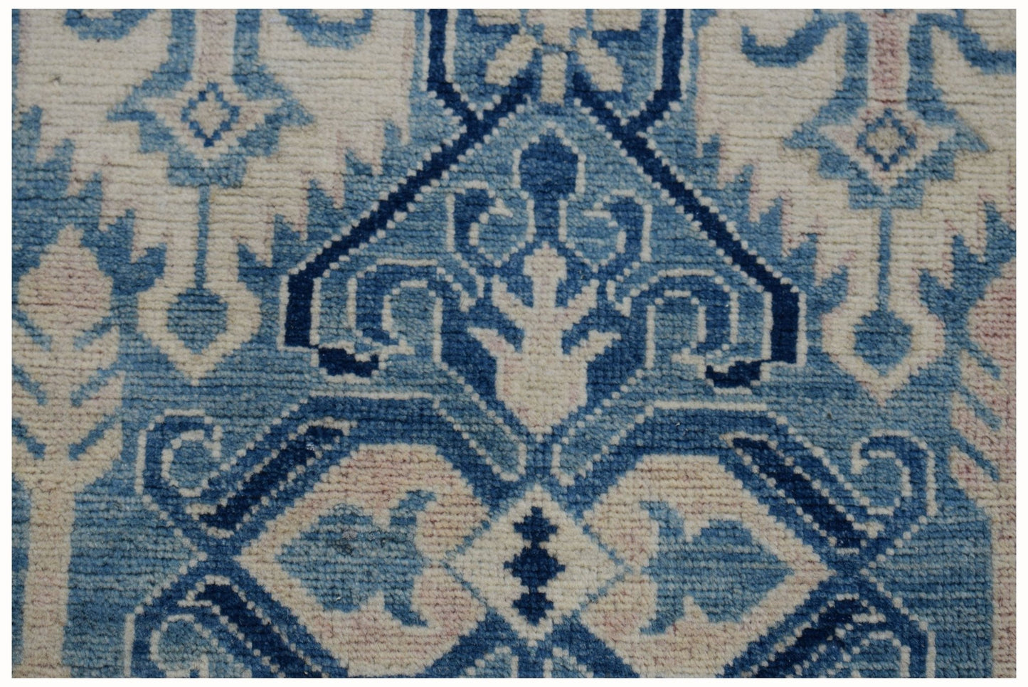 A handmade Afghan Kazakh runner featuring a geometric pattern in shades of blue and beige.