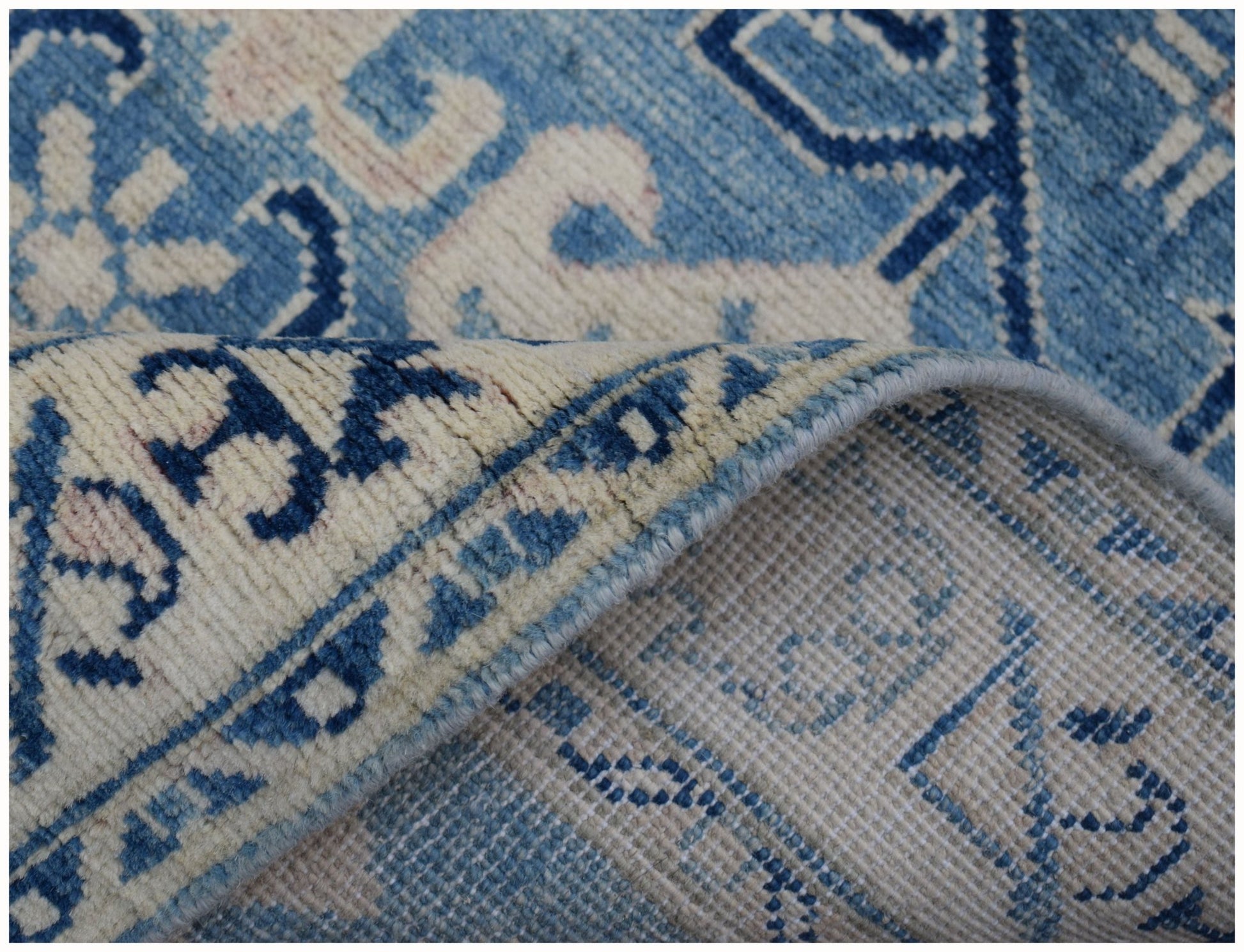 A handmade Afghan Kazakh runner rug featuring a blue and beige geometric pattern.