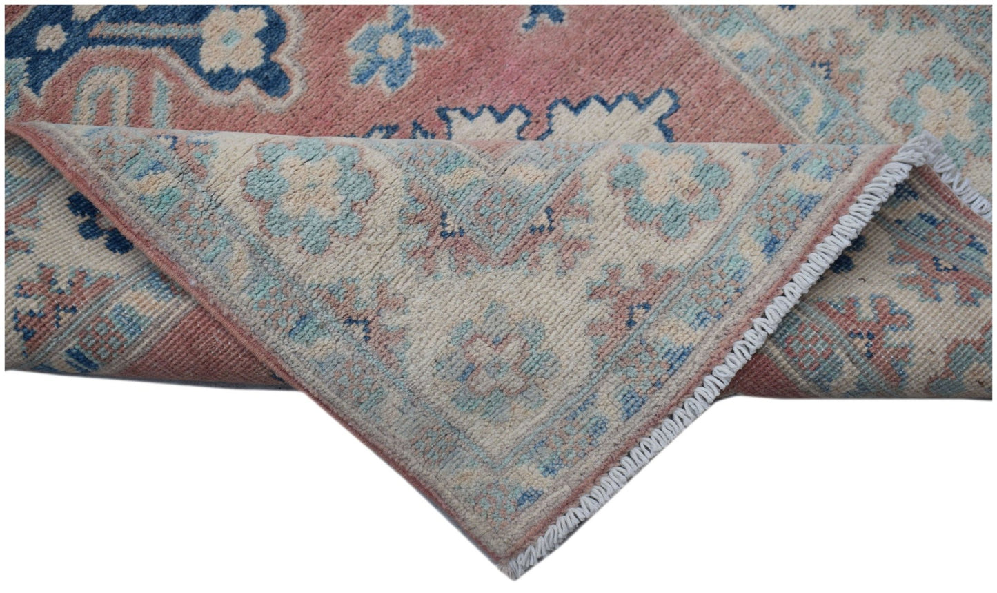 A handmade Afghan Kazakh runner featuring traditional floral motifs in pink, blue, and cream wool.