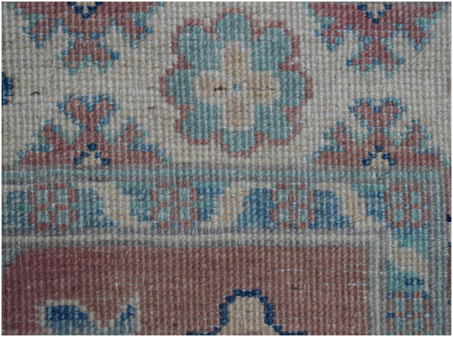 A handmade Afghan Kazakh runner featuring traditional floral motifs in blue, pink, and cream wool.