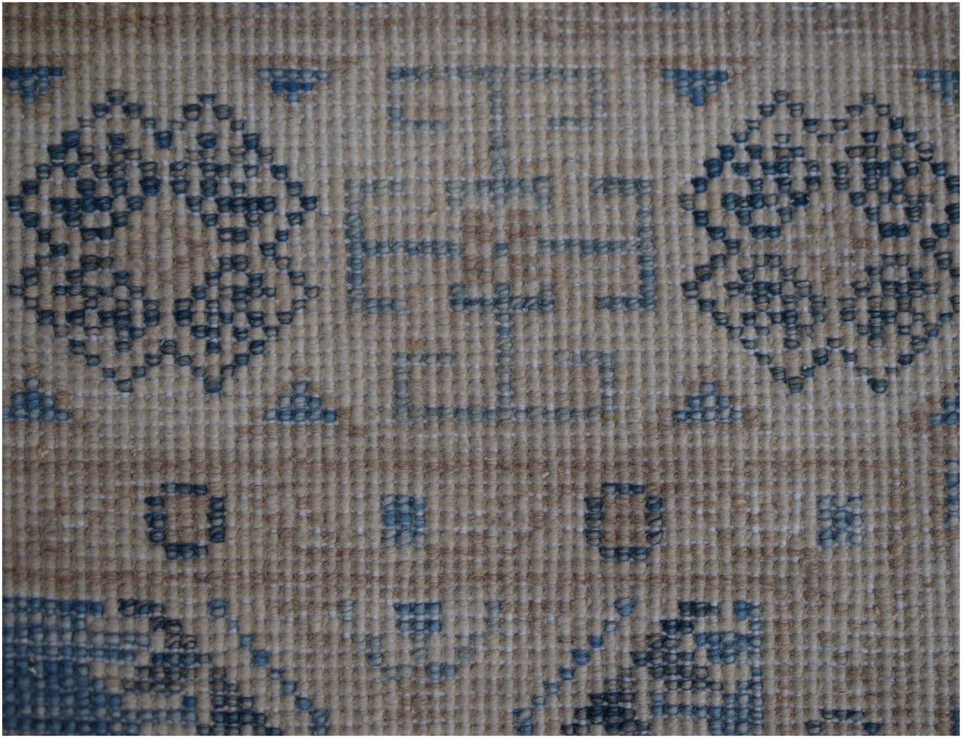 A handmade Afghan Kazakh runner featuring a beige wool base with intricate blue geometric patterns.