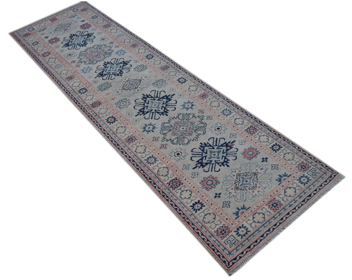 A handmade Afghan Kazakh runner rug featuring traditional geometric motifs in blue and pink.
