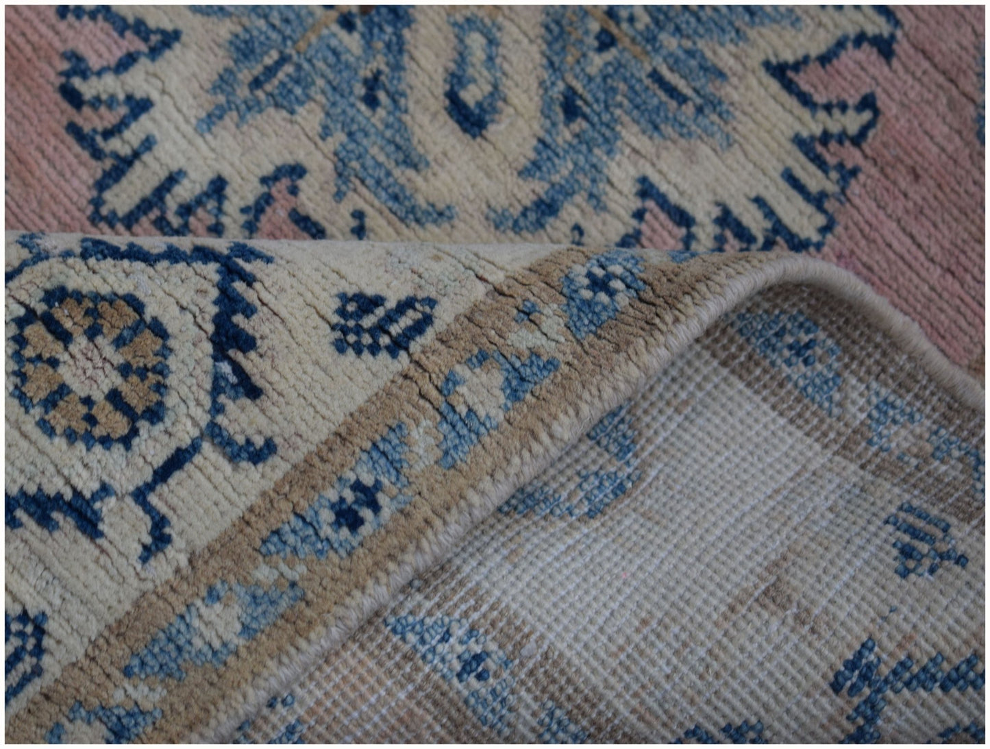 A handmade Afghan Kazakh runner featuring a beige, blue, and pink geometric pattern.