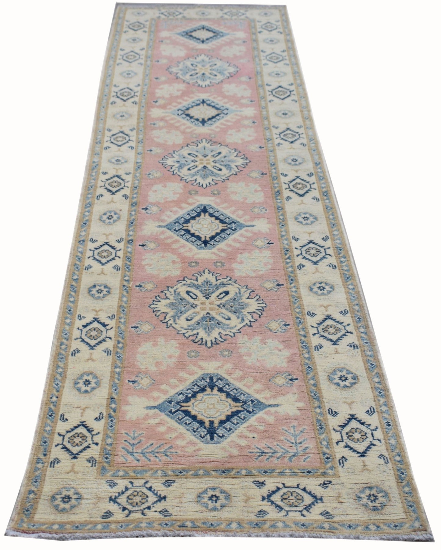 A handmade Afghan Kazakh runner rug featuring a pink center with blue and beige geometric motifs.