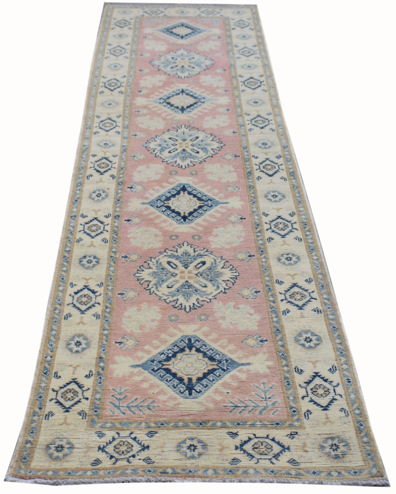 A handmade Afghan Kazakh runner rug featuring a pink center with blue and beige geometric motifs.