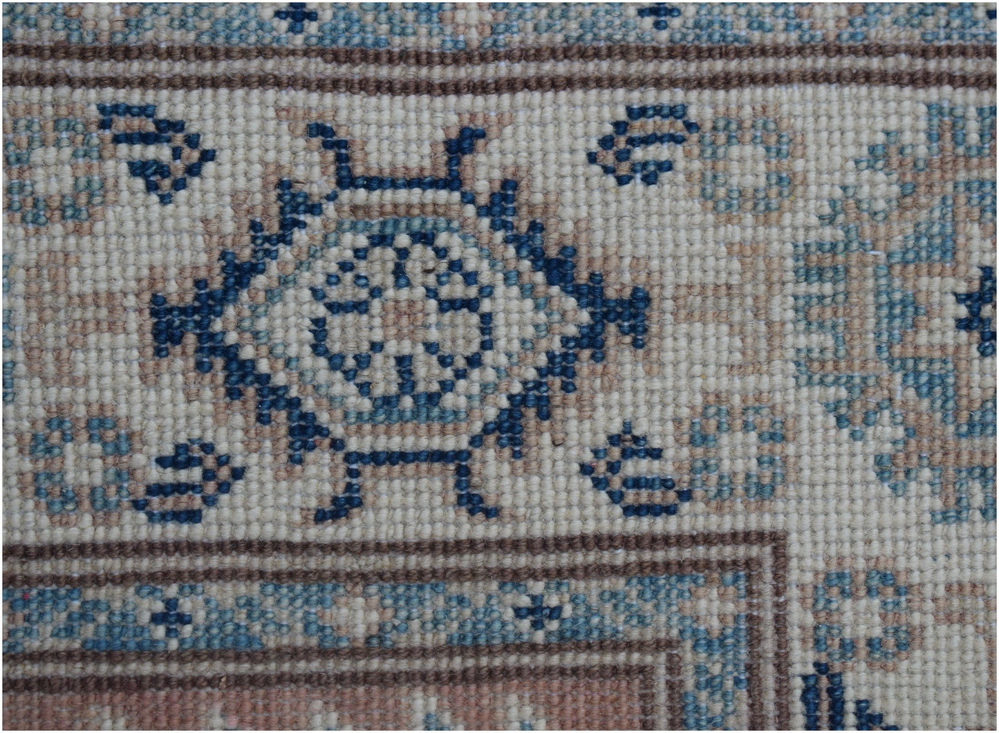 A close-up of an Afghan Kazakh runner featuring traditional blue and beige geometric motifs.