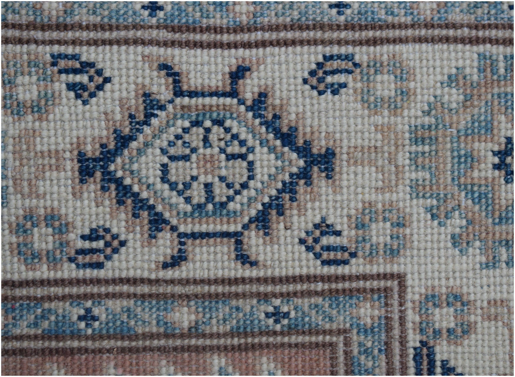 A close-up of an Afghan Kazakh runner featuring traditional blue and beige geometric motifs.