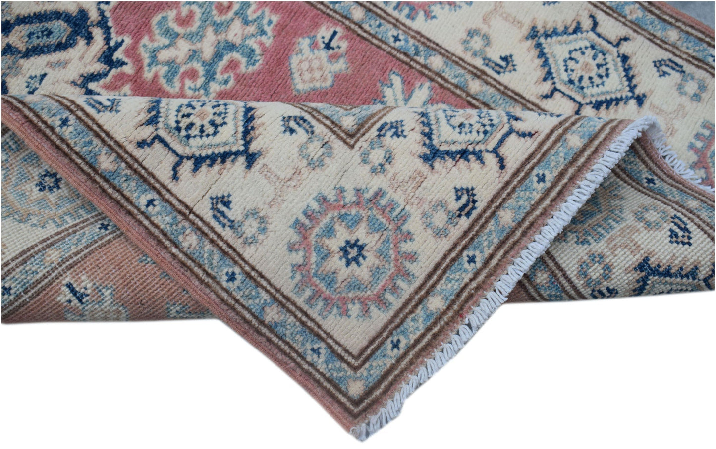A handmade Afghan Kazakh runner featuring traditional geometric motifs in pink, blue, and cream.
