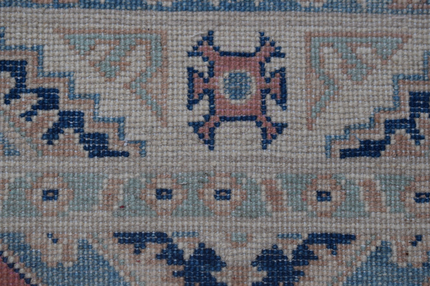 A close-up of a handmade Afghan Kazakh runner featuring traditional geometric motifs in wool.