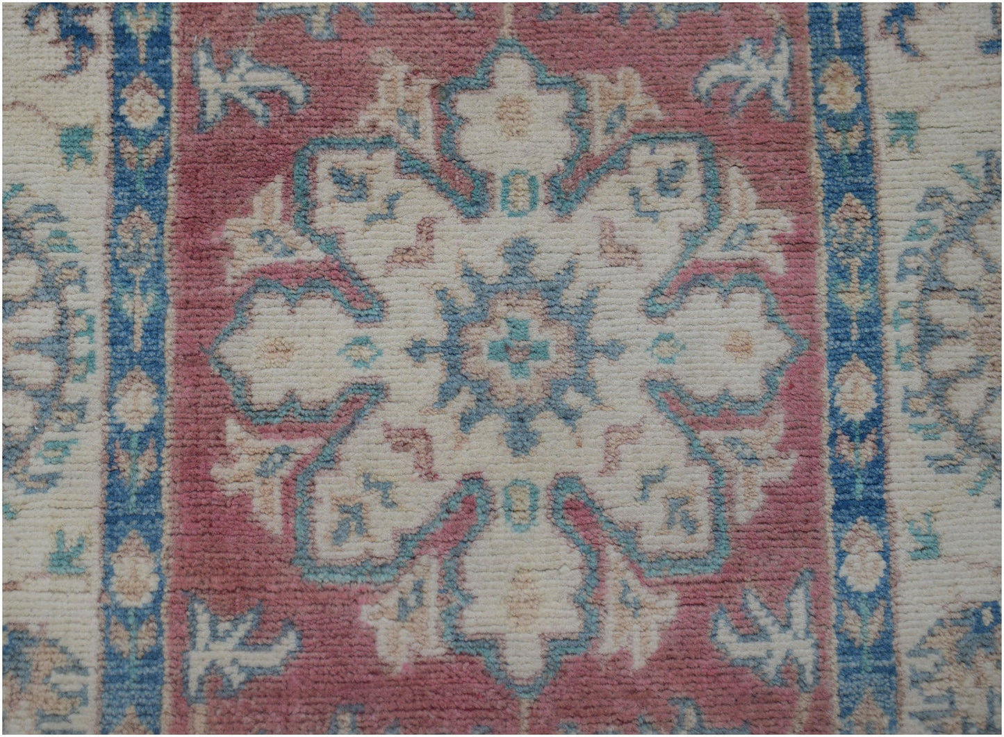 Handmade Afghan Kazakh runner featuring a central floral medallion in pink, blue, and cream wool.