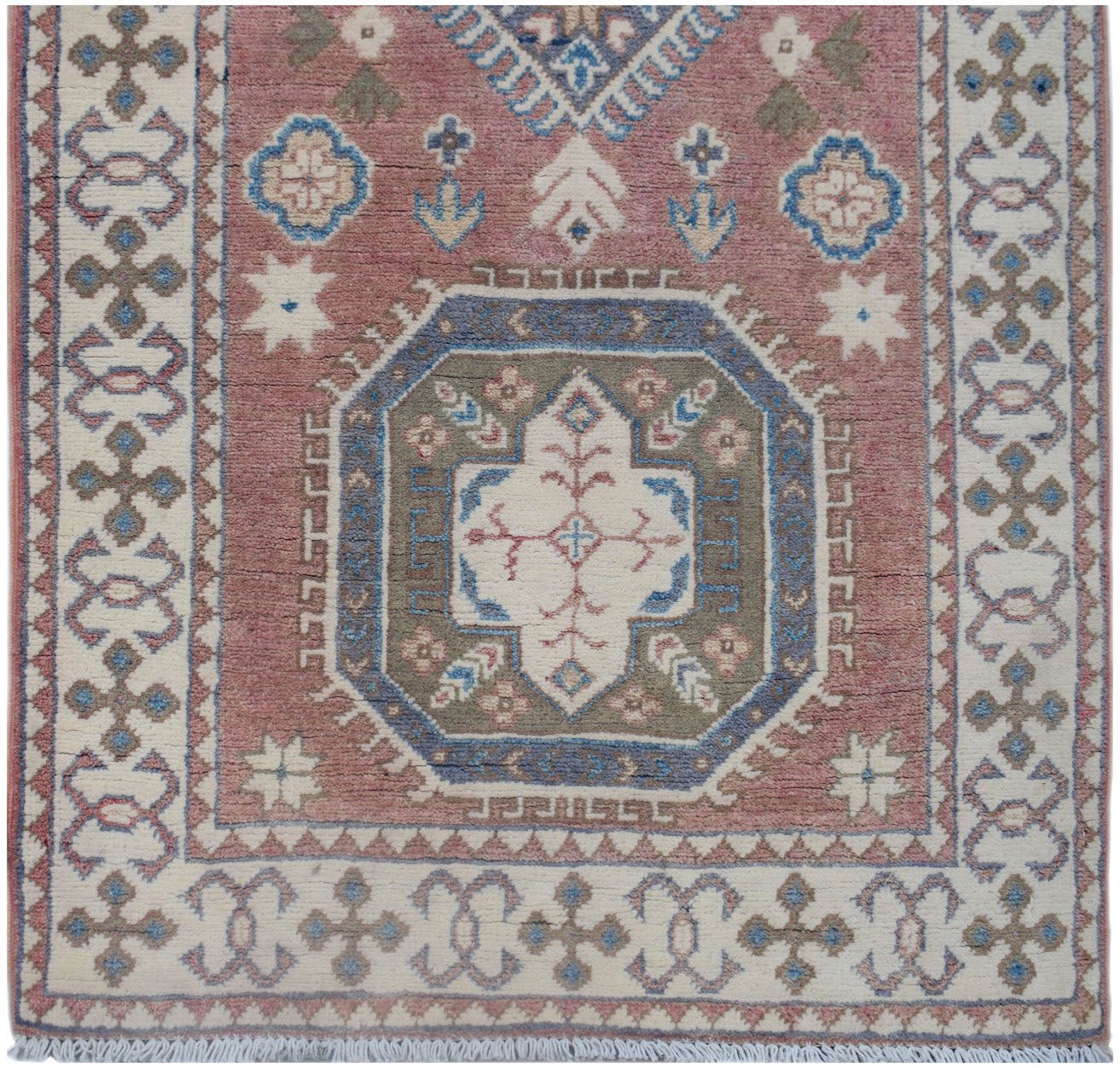 Handmade Afghan Kazakh runner featuring a central geometric medallion on a dusty pink background.