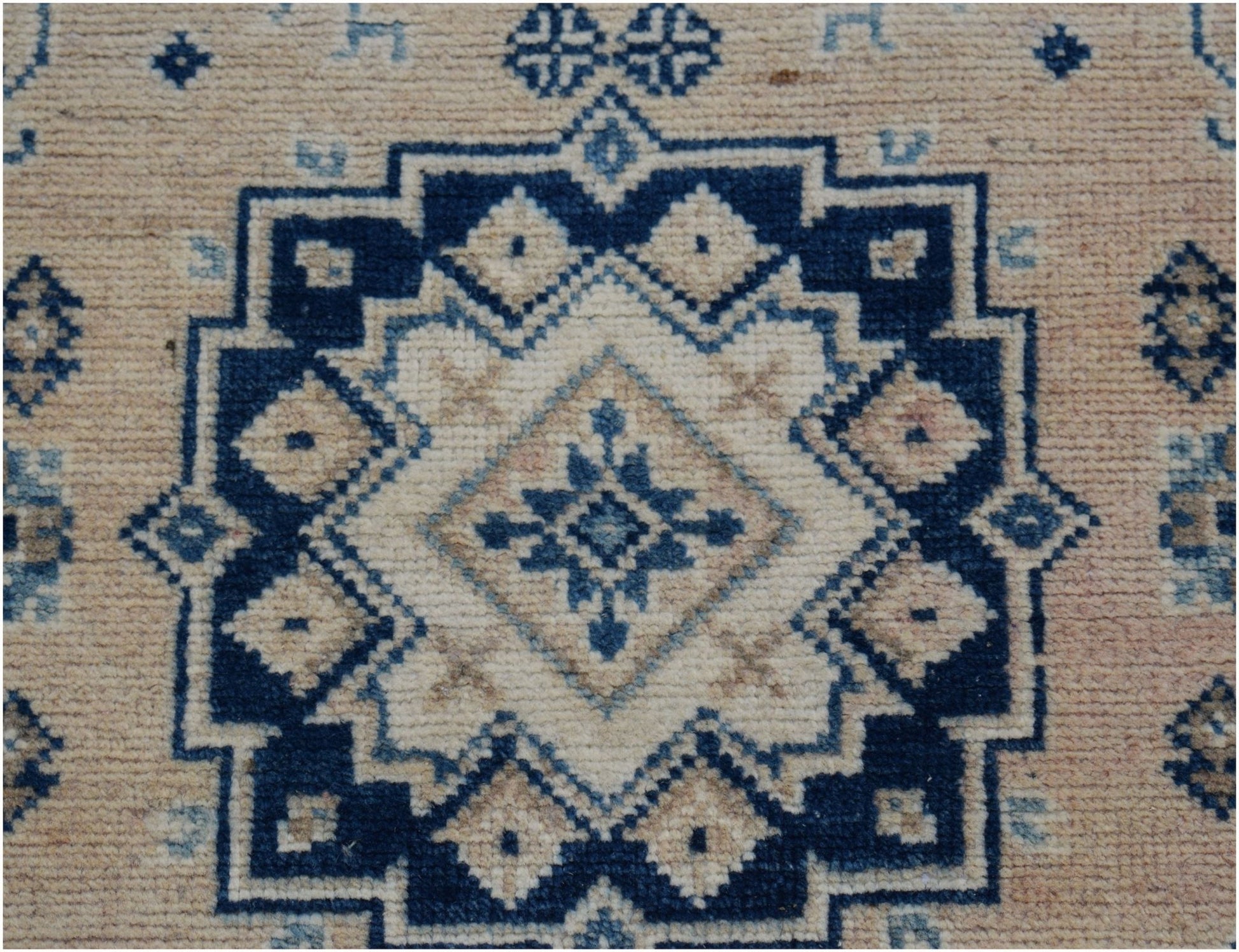 A handmade Afghan Kazakh runner featuring a geometric blue and cream medallion pattern.
