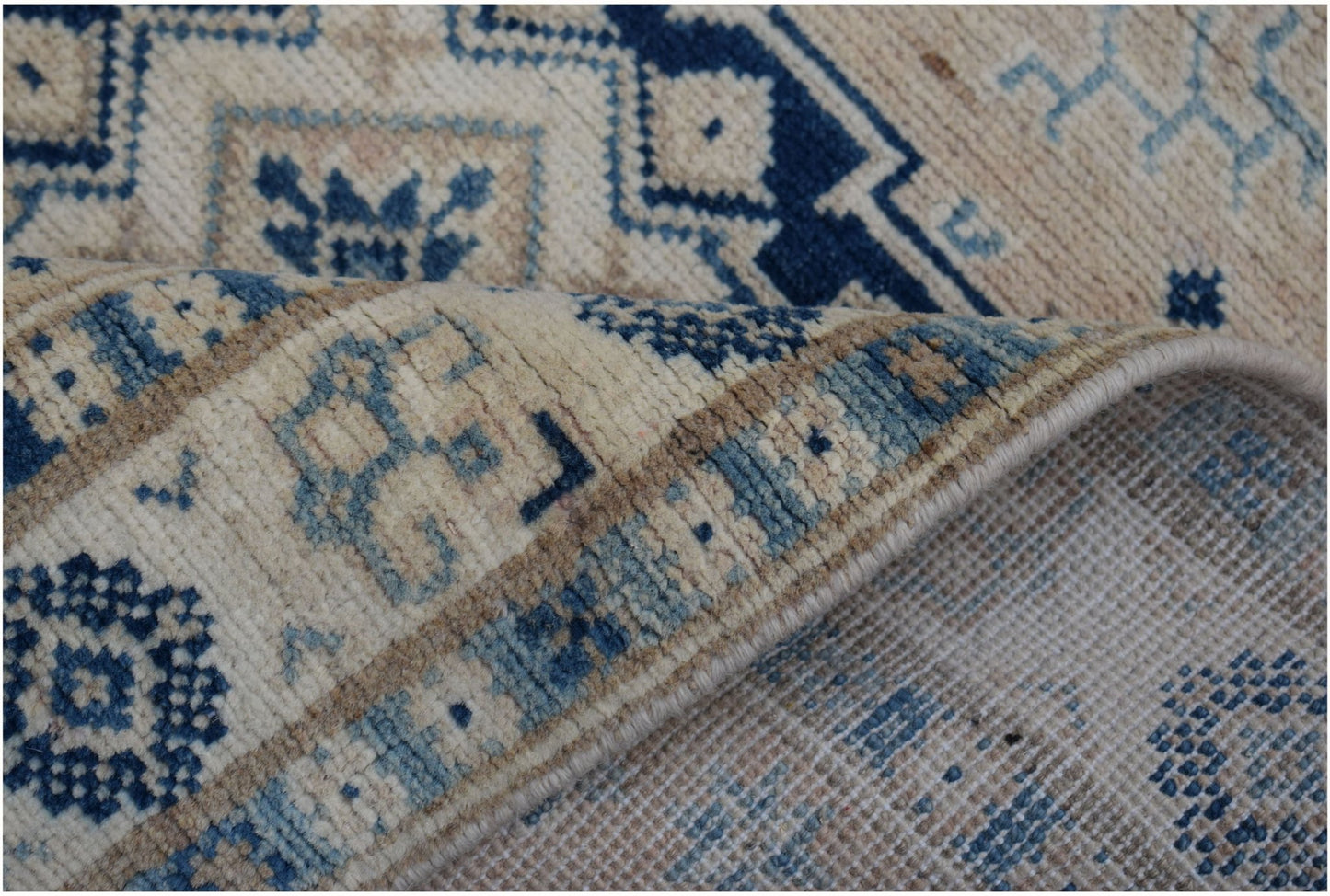 A handmade Afghan Kazakh runner featuring traditional geometric patterns in blue and cream wool.