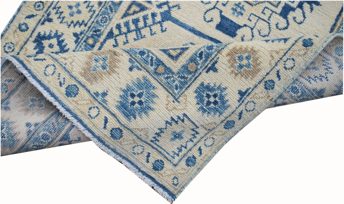 A handmade Afghan Kazakh runner featuring traditional blue and beige geometric patterns.