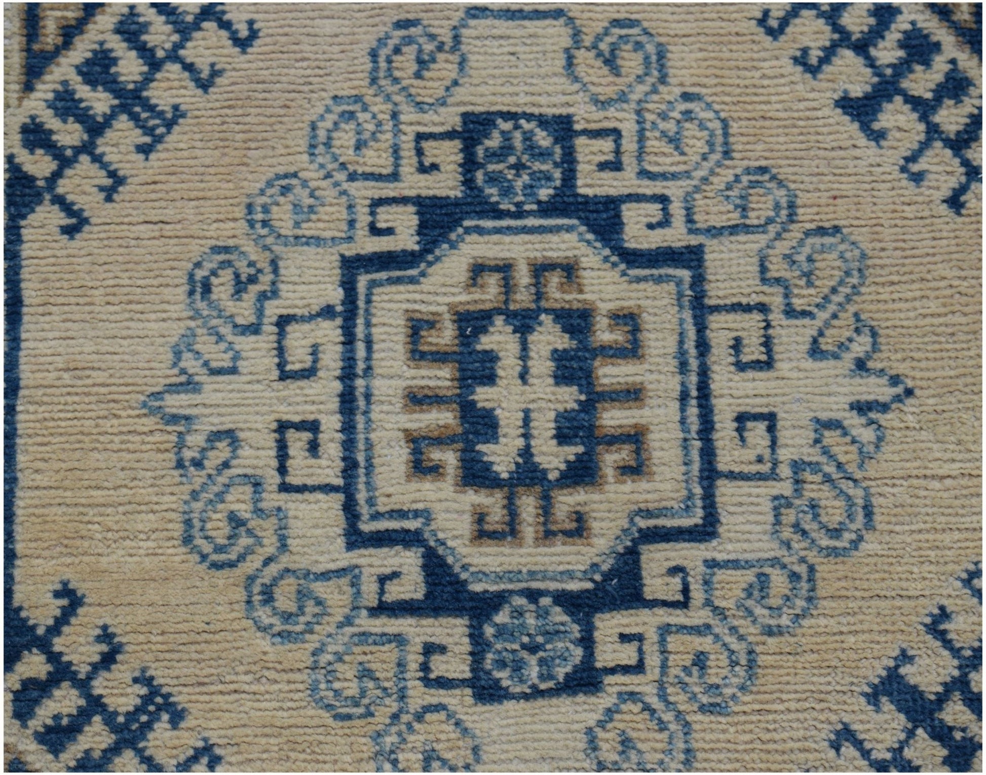 A handmade Afghan Kazakh runner featuring a central blue and beige geometric medallion pattern.