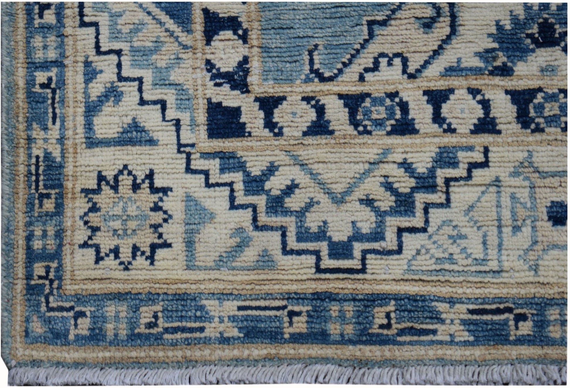 Handmade Afghan Kazakh runner rug featuring a geometric blue and beige pattern with fringe.