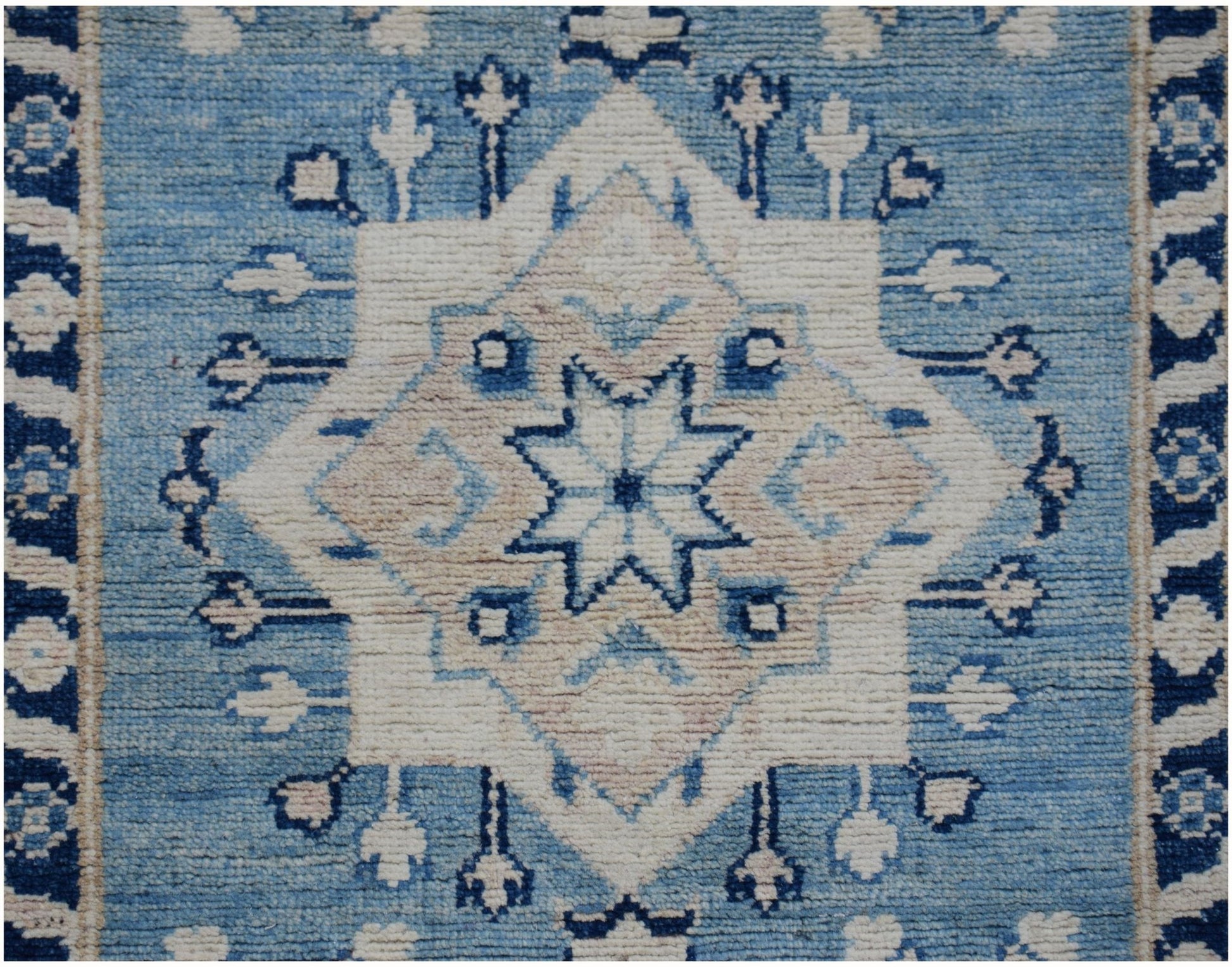 An Afghan Kazakh runner rug featuring a central geometric star motif in shades of blue and beige.