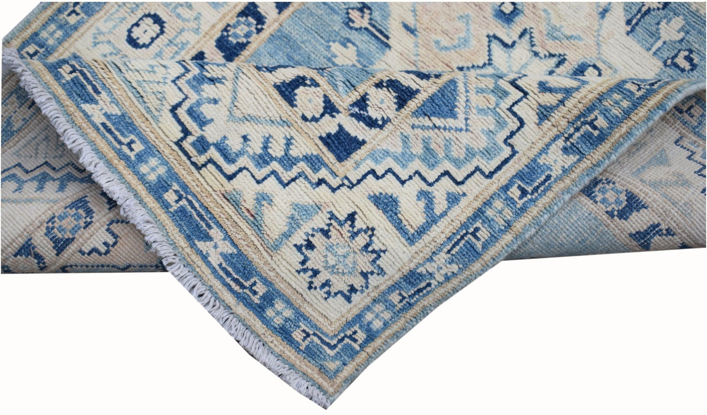 A handmade Afghan Kazakh runner rug featuring a geometric pattern in shades of blue and beige.