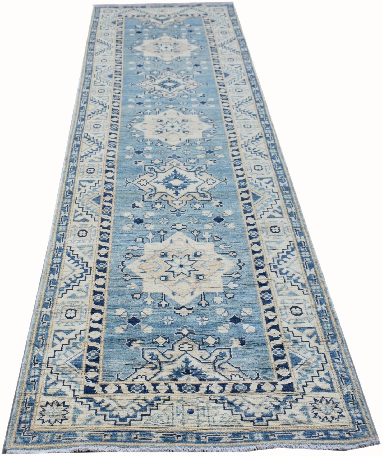 A handmade Afghan Kazakh runner rug featuring a blue and beige geometric medallion pattern.