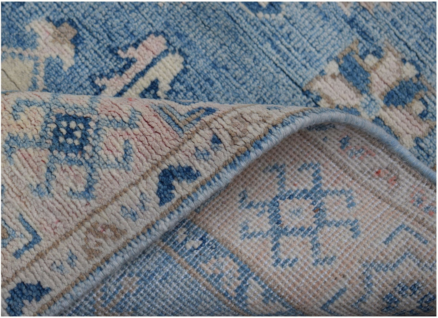 A handmade Afghan Kazakh runner featuring traditional blue and cream geometric patterns.
