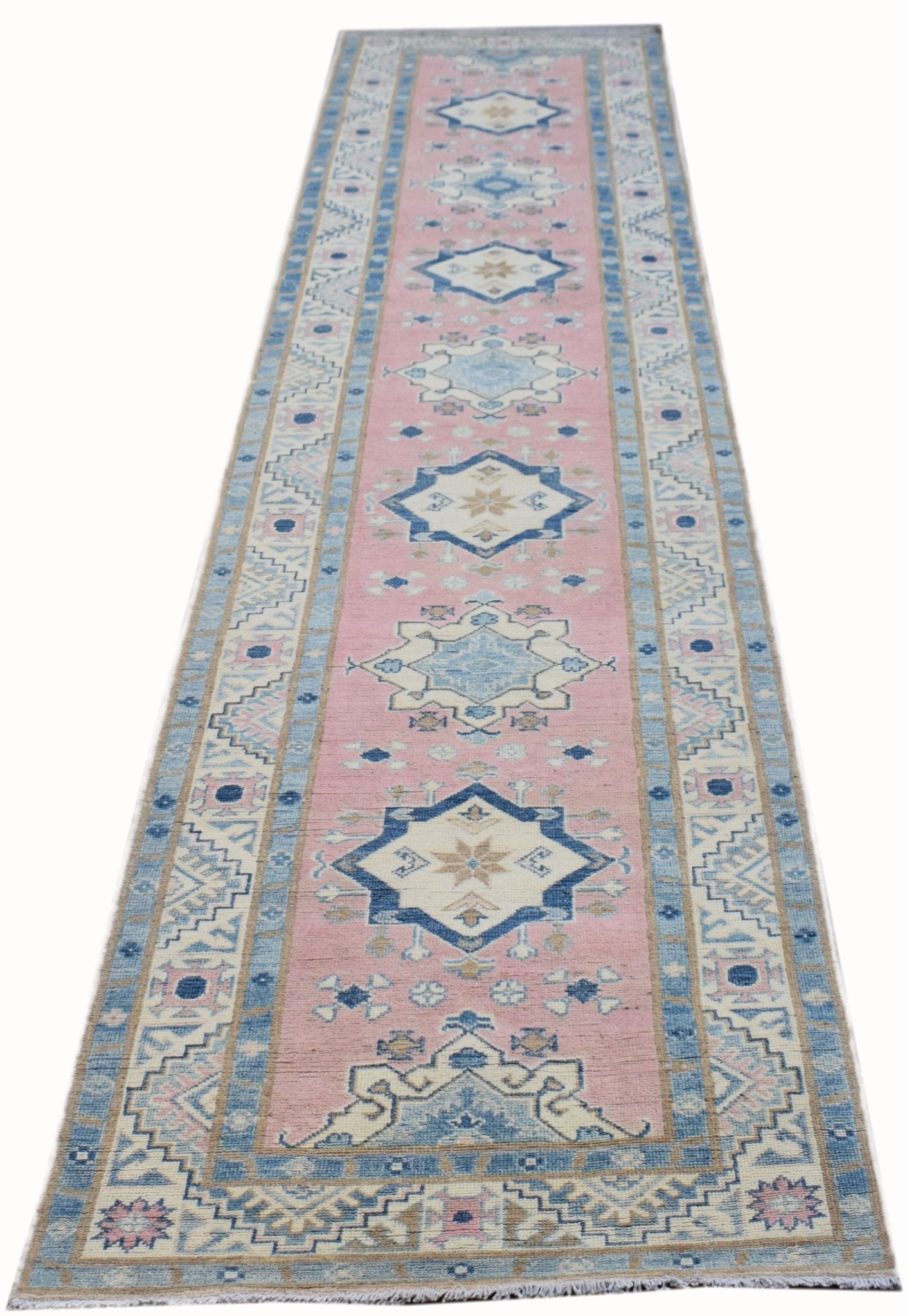 A handmade Afghan Kazakh runner rug featuring geometric medallions in pink, blue, and beige.