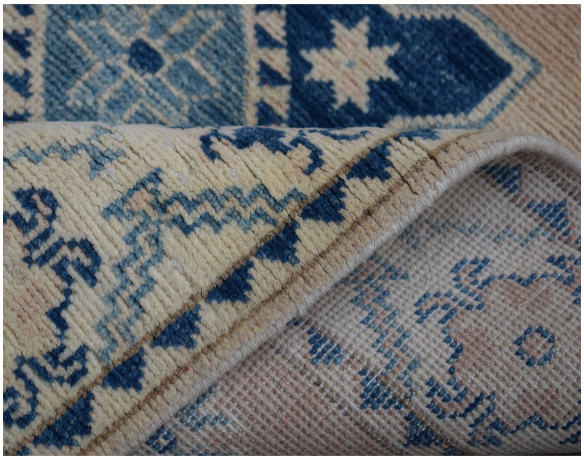 A handmade Afghan Kazakh runner rug featuring a geometric blue and beige pattern.