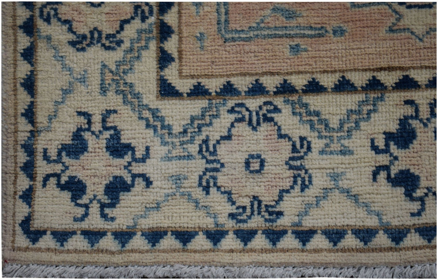 A close-up of an Afghan Kazakh runner rug featuring a geometric floral pattern in blue and beige.