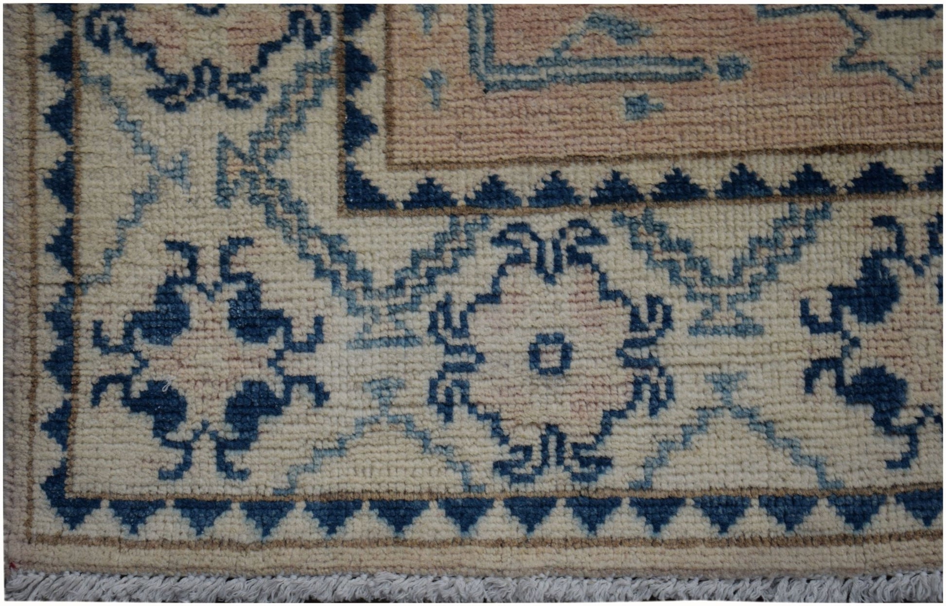 A close-up of an Afghan Kazakh runner rug featuring a geometric floral pattern in blue and beige.