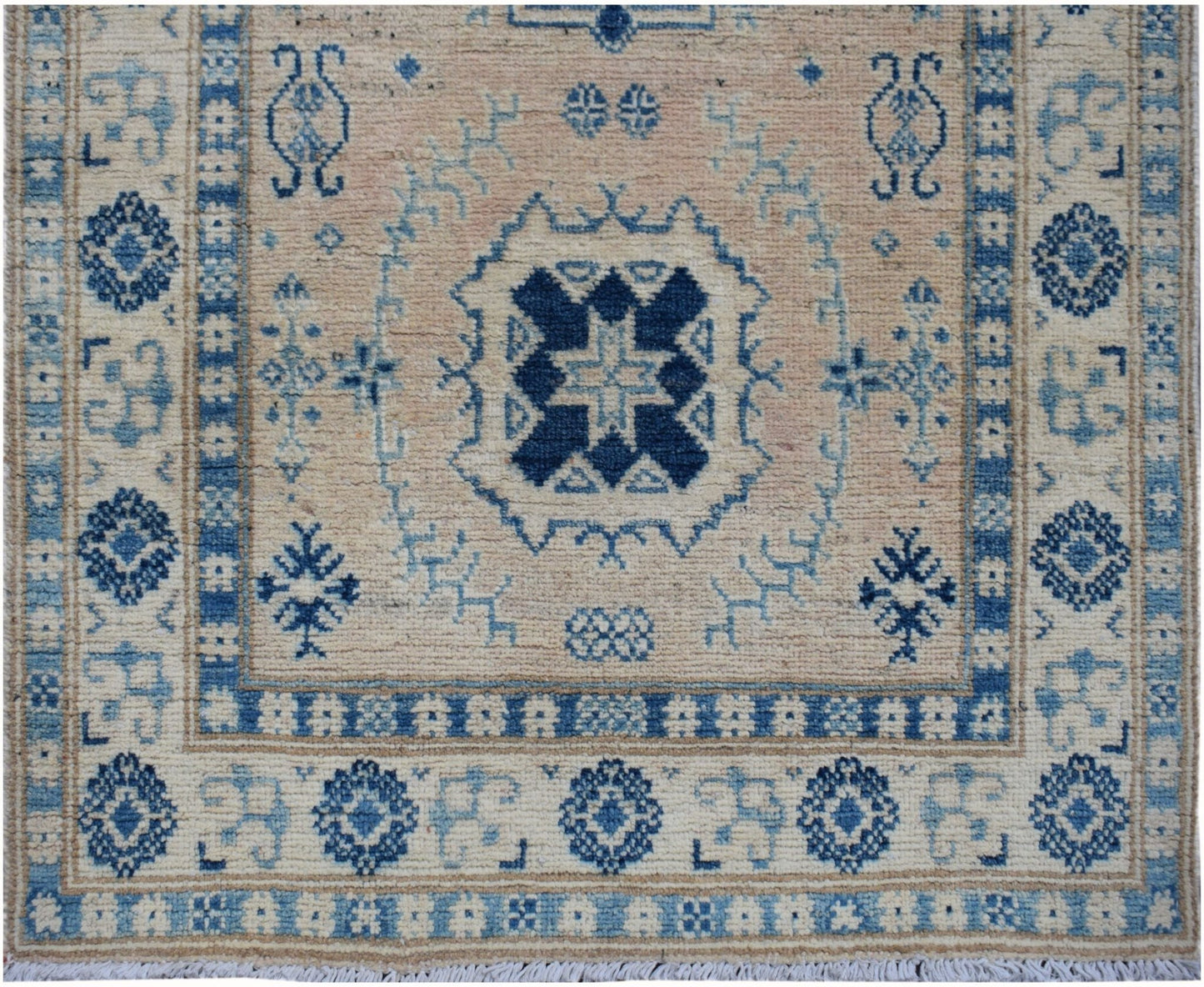 Handmade Afghan Kazakh runner featuring a central blue geometric medallion on a beige wool field.