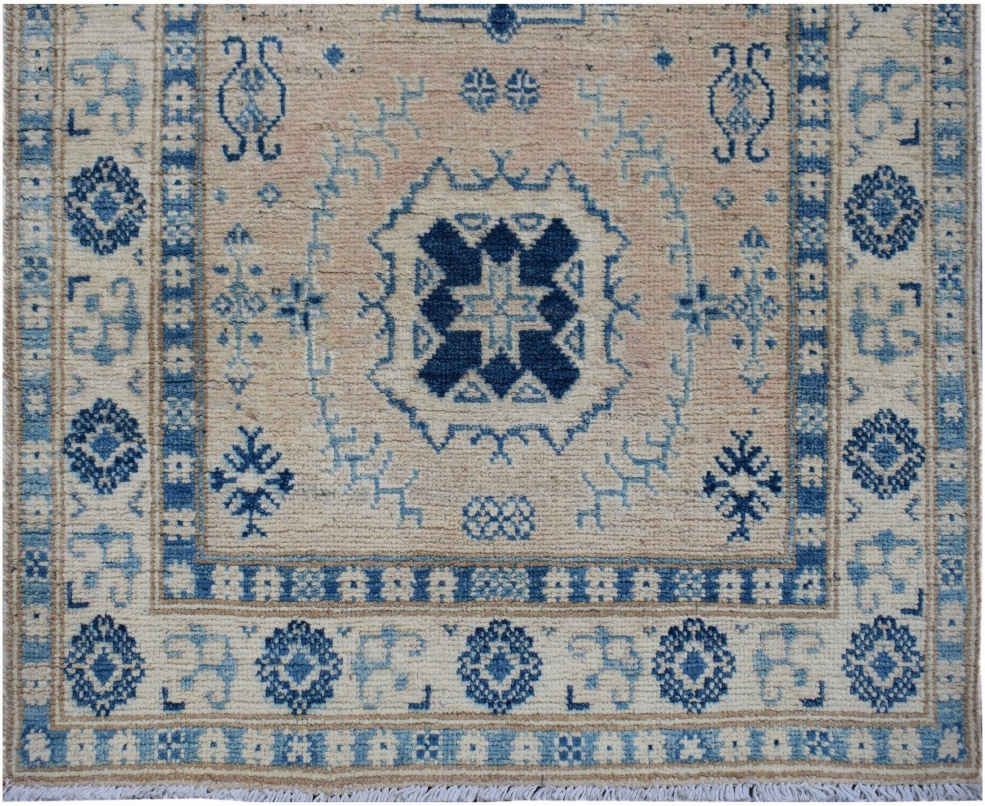 Handmade Afghan Kazakh runner featuring a central blue geometric medallion on a beige wool field.