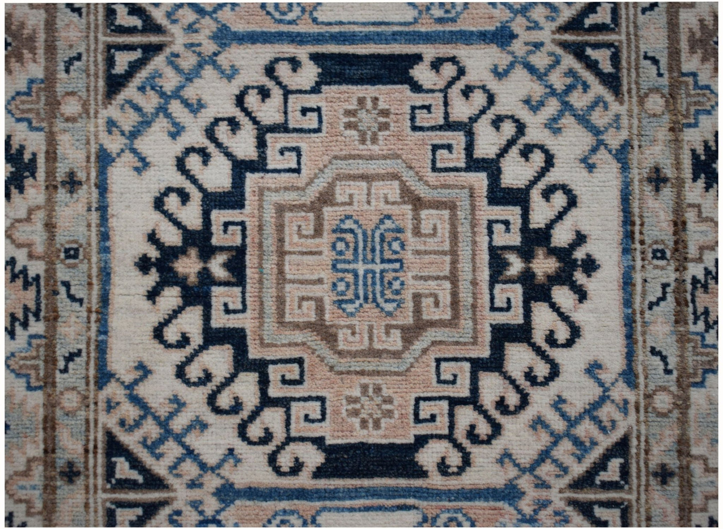 An Afghan Kazakh runner rug featuring a geometric medallion pattern in beige, blue, and grey.