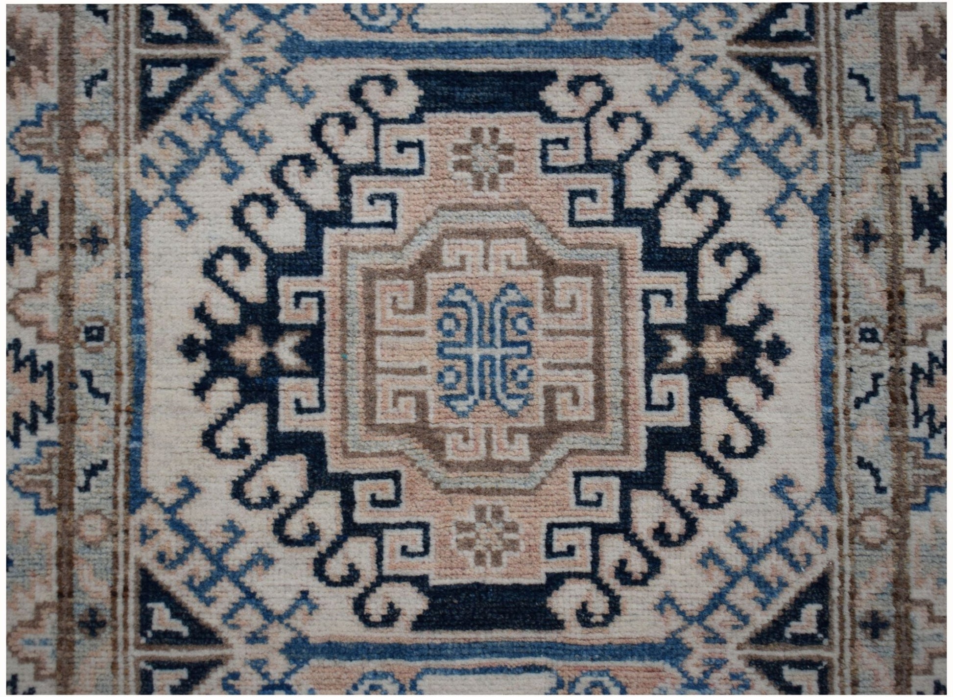 An Afghan Kazakh runner rug featuring a geometric medallion pattern in beige, blue, and grey.