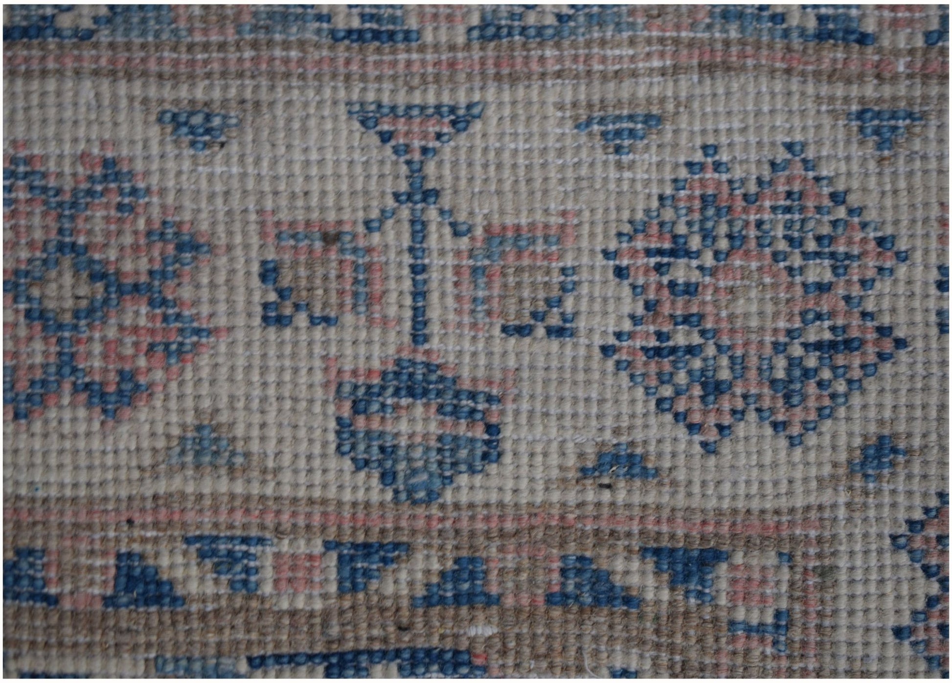 A close-up of an Afghan Kazakh runner rug featuring geometric floral patterns in blue and pink.