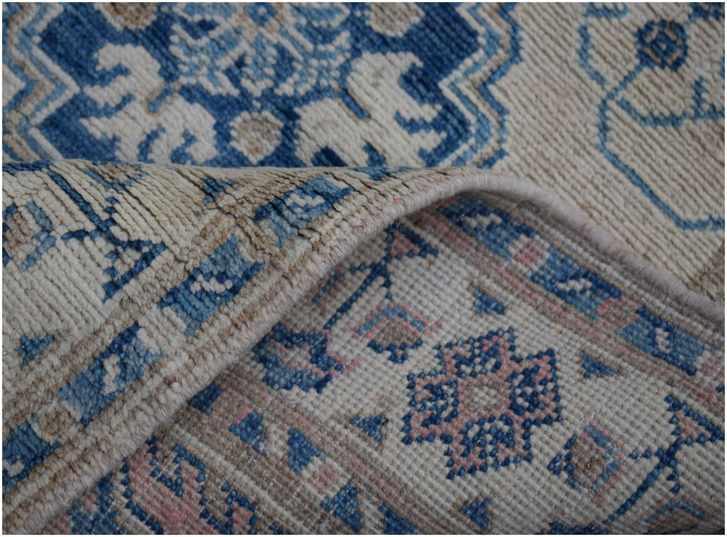 A handmade Afghan Kazakh runner featuring a geometric pattern in blue, beige, and soft pink.